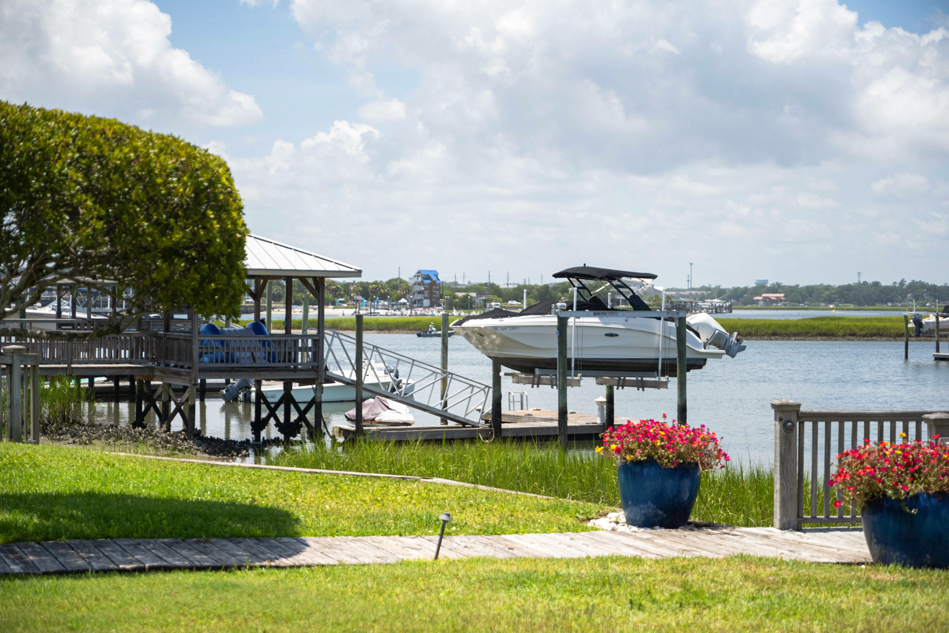 Boating in Wrightsville Beach – Insurance-Ready Dockside Scene Docked boat on lift in Wrightsville Beach, NC, with gazebo, flowers, and calm waterway view.