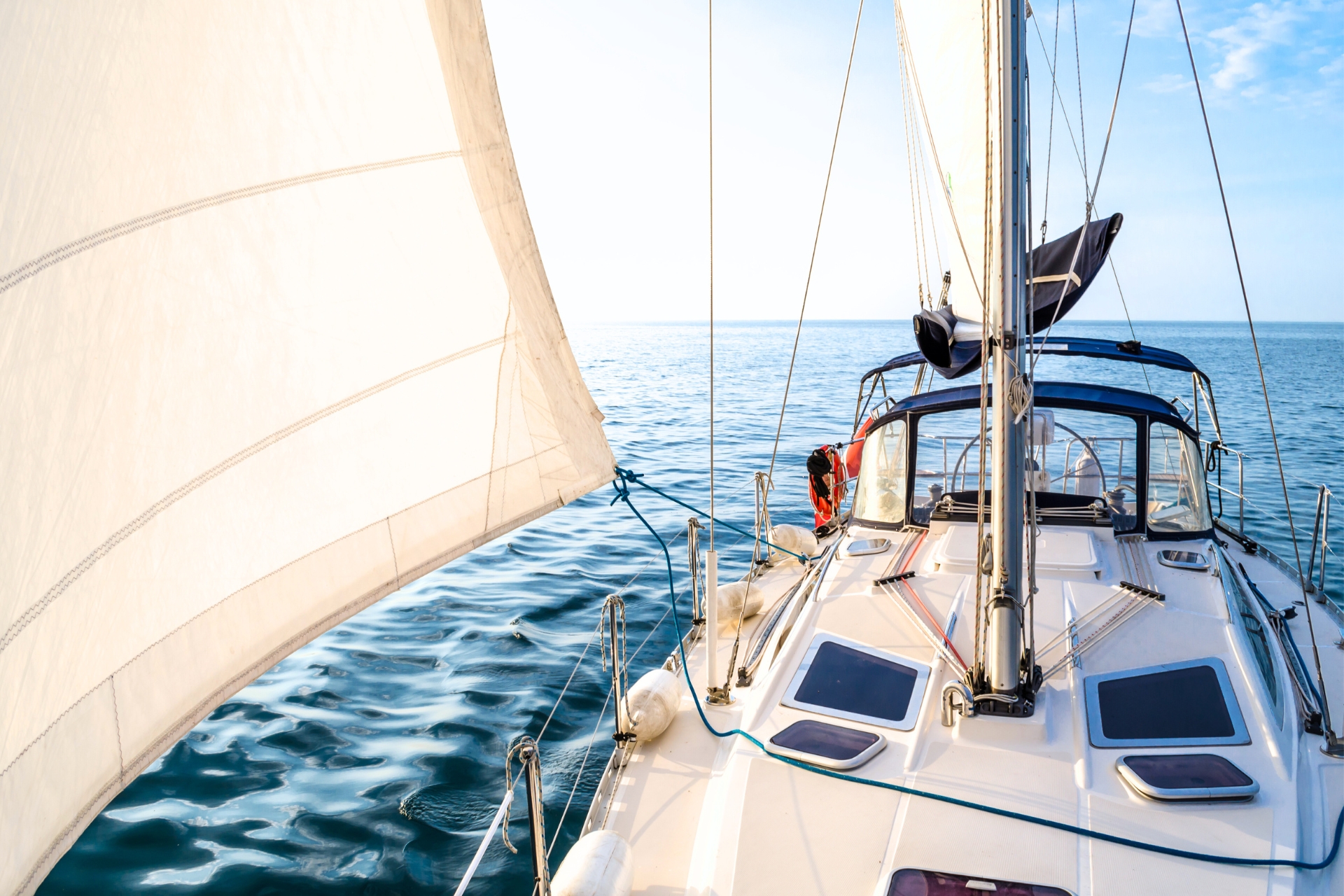 Luxury sailboat cruising on calm blue water under clear skies, symbolizing high-value asset protection and lifestyle coverage.