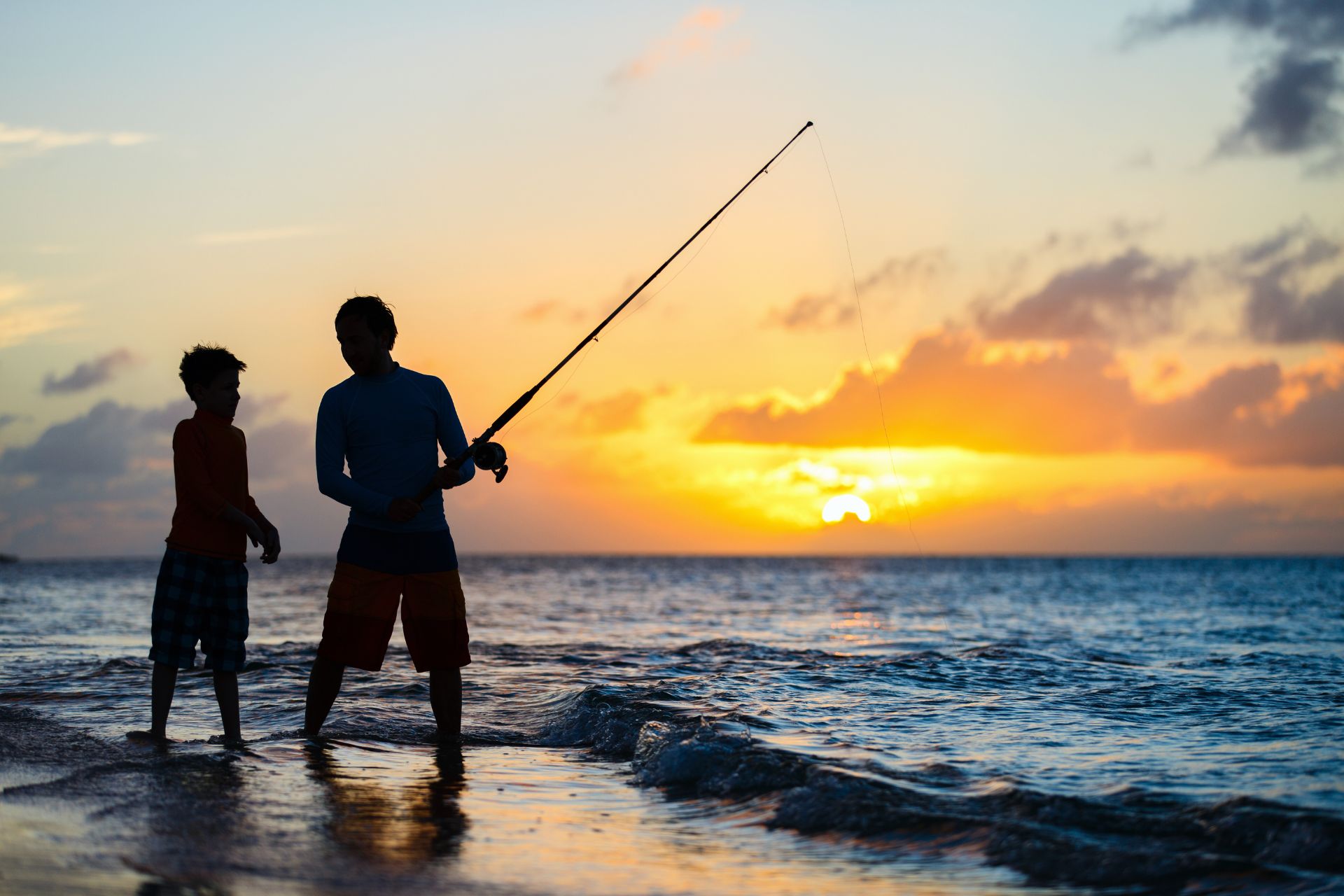 Brothers fishing together at sunset along the beach, symbolizing protection and lasting memories for life insurance coverage.