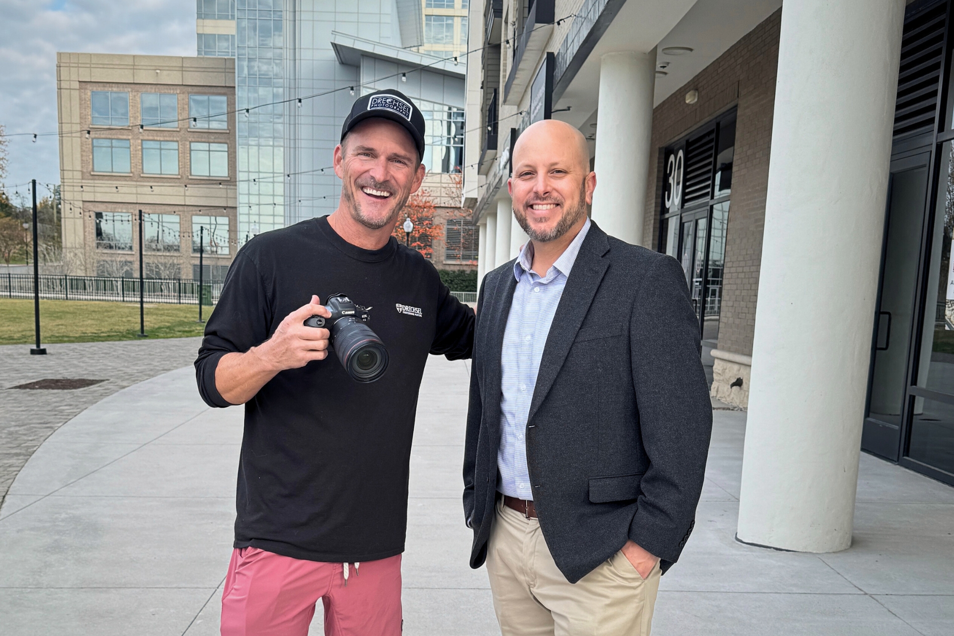 Local photographer TJ standing with a FinPoint Insurance agent outside a commercial building, showcasing a real business client.