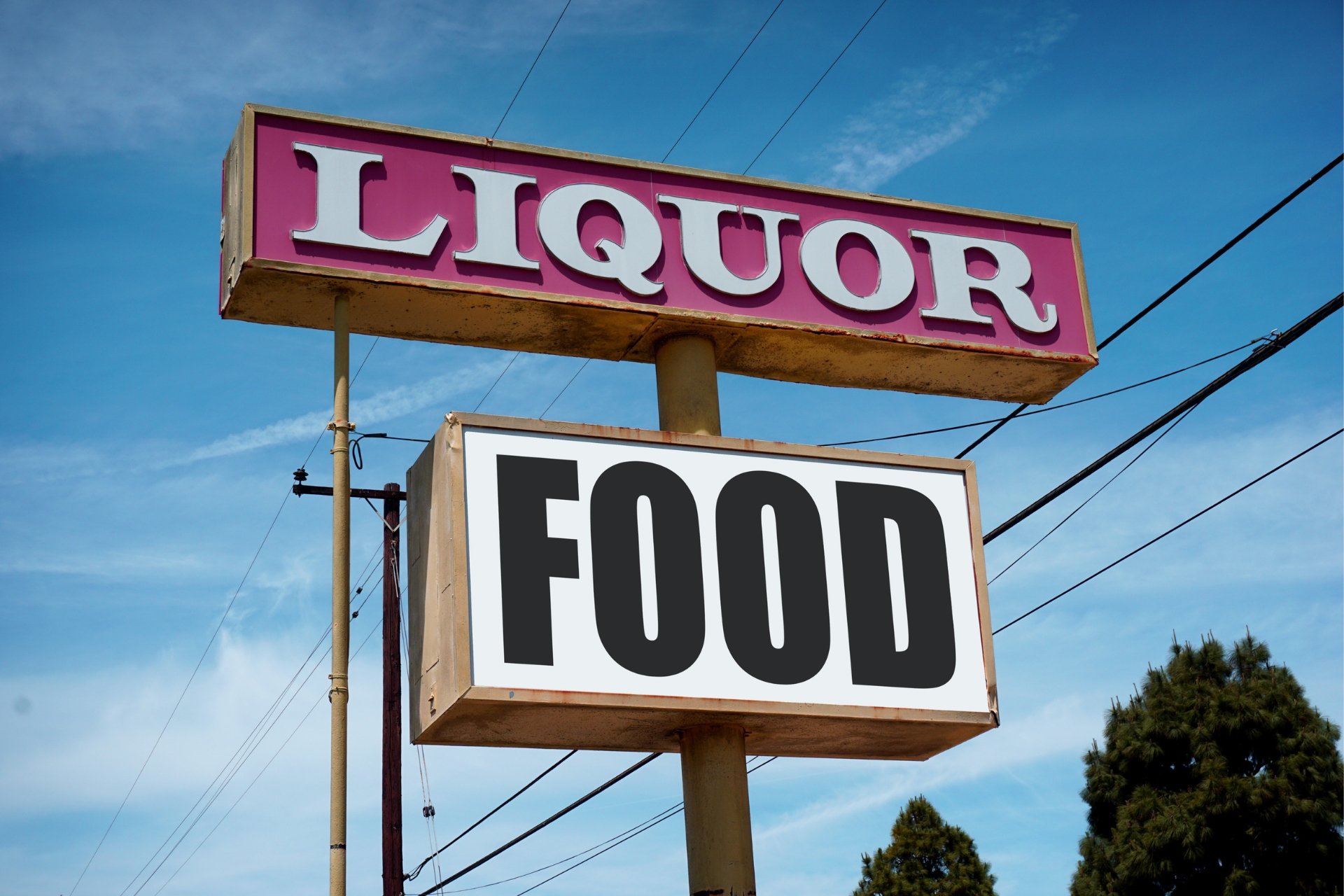 Vintage roadside sign displaying Liquor and Food against a blue sky.