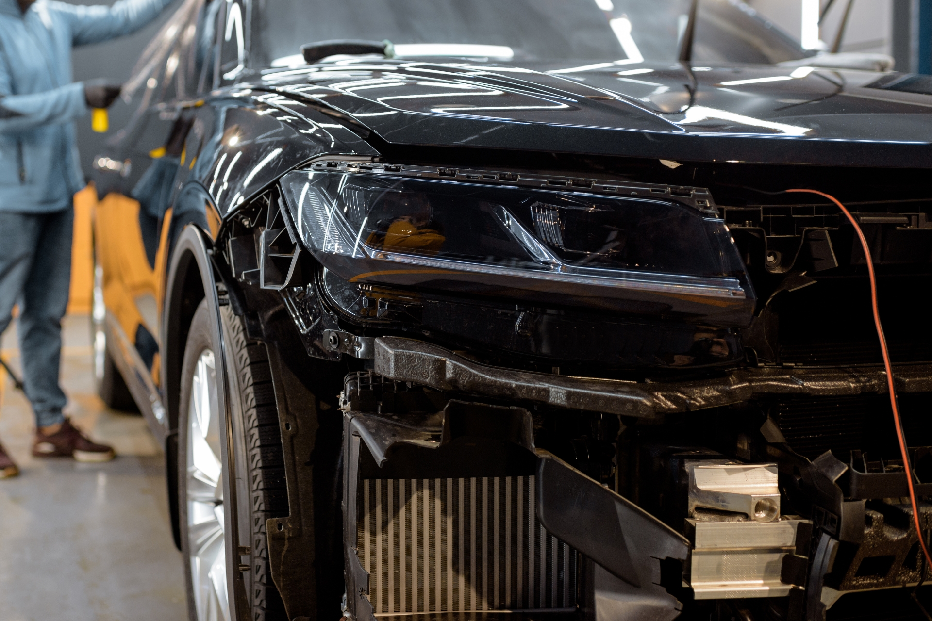 Automotive body repair technician working on damaged front end of vehicle in collision repair shop