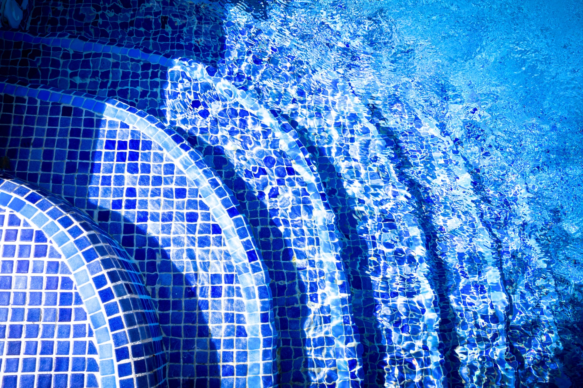 Blue tile inground swimming pool steps with water detail