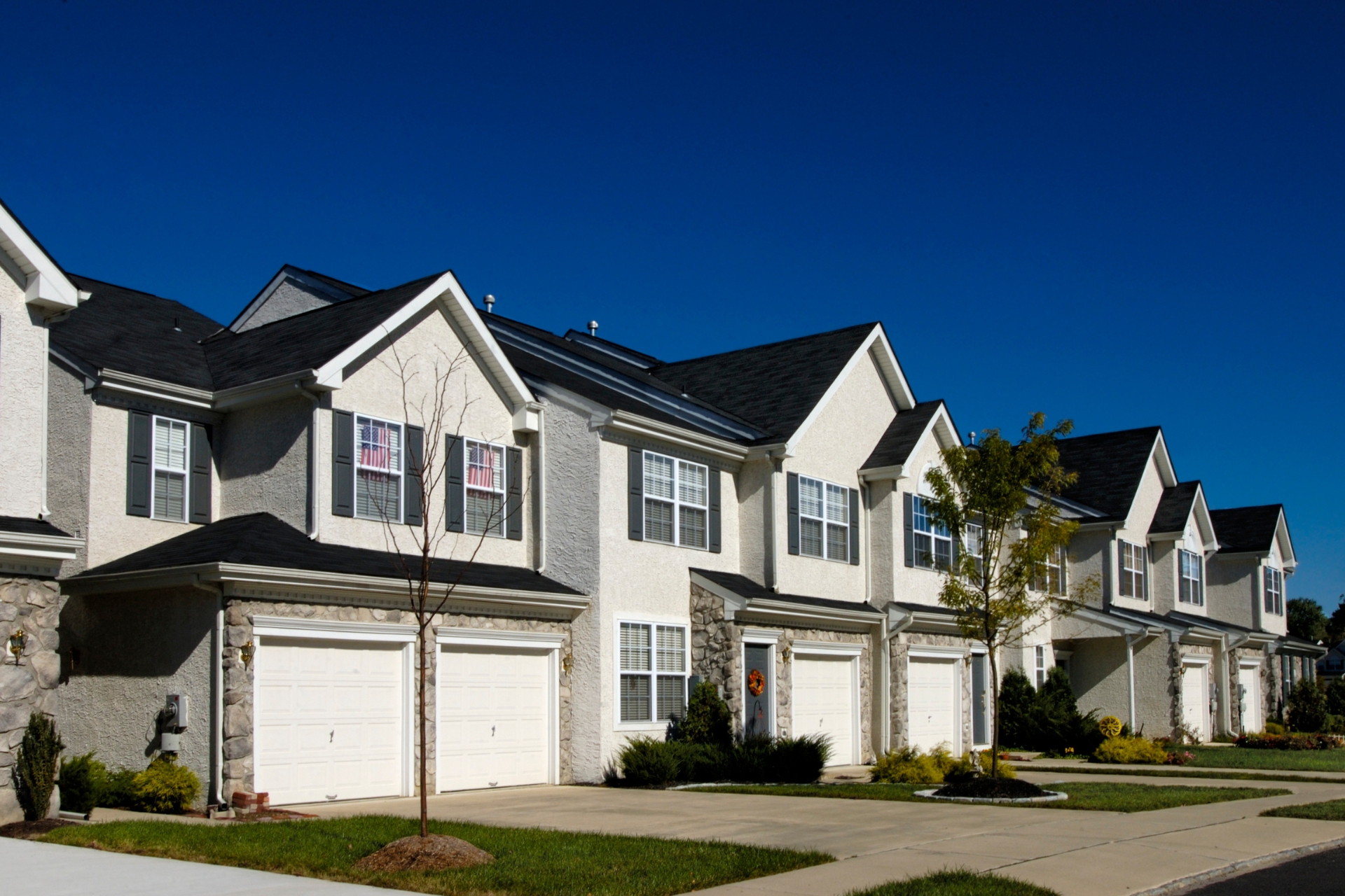 Row of modern townhomes with garages representing condo association property insurance