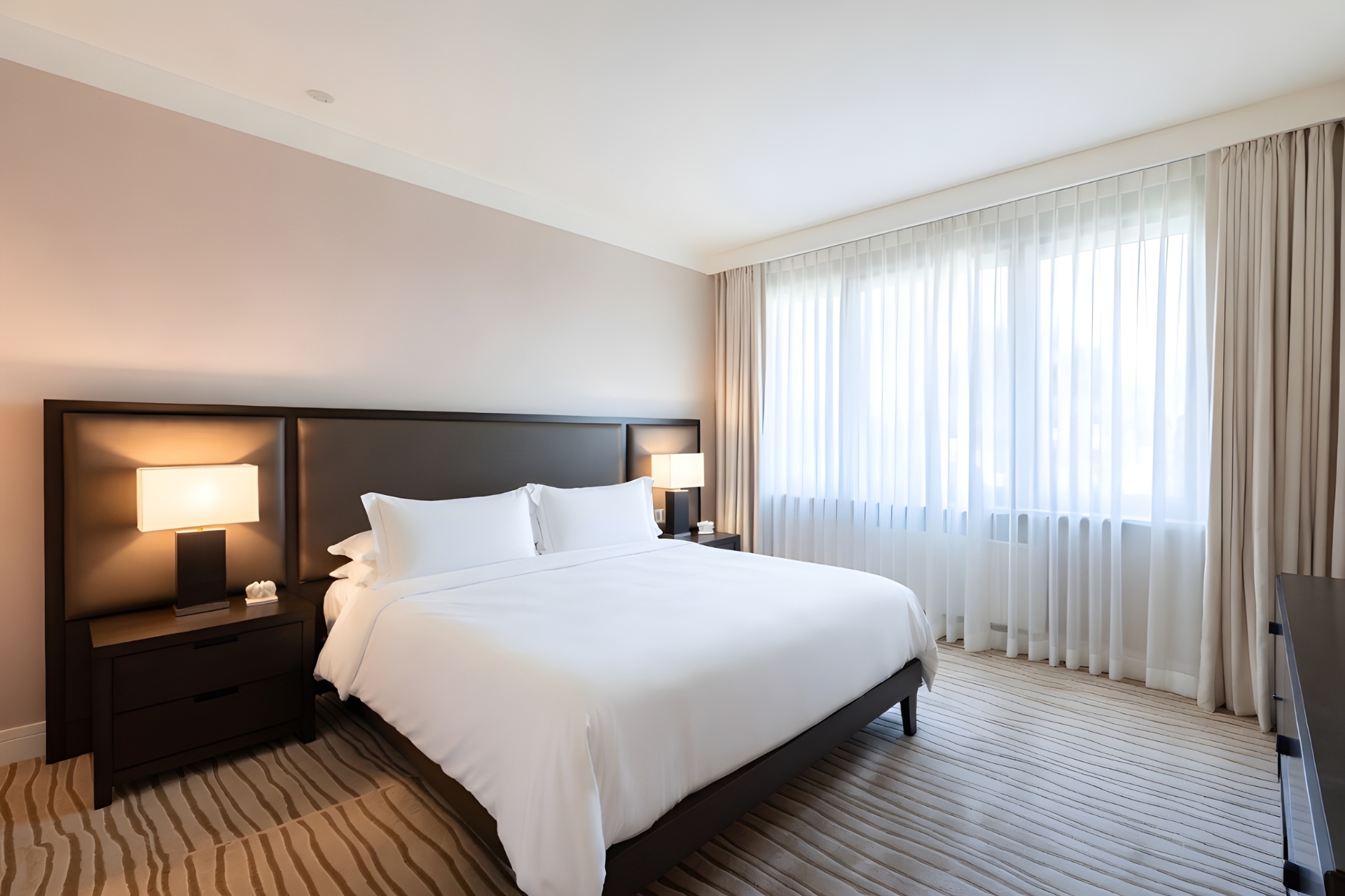Modern hotel room with king bed, clean interior design, and natural lighting for hospitality and lodging businesses