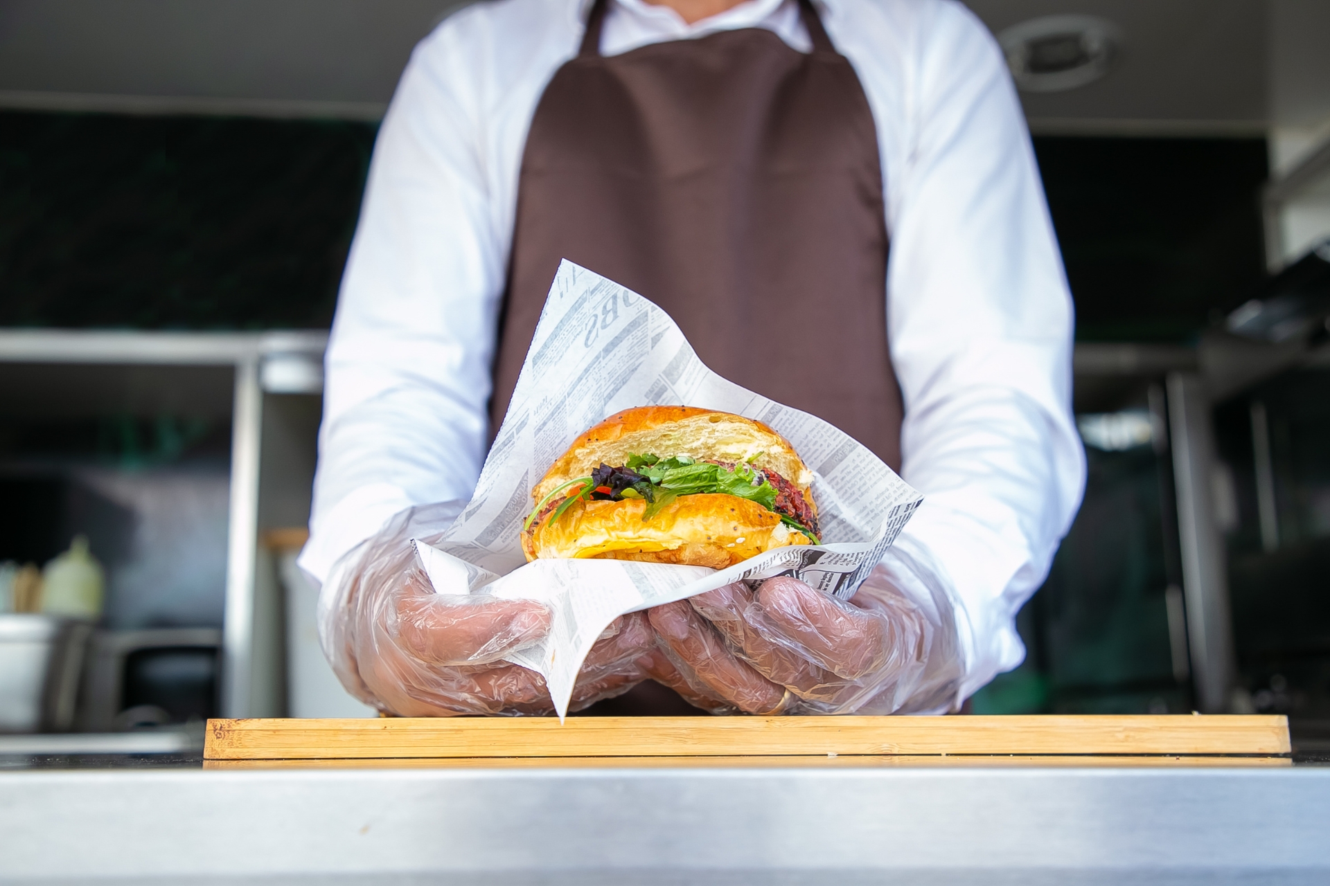 Food truck worker preparing and serving a sandwich with gloves inside a mobile kitchen