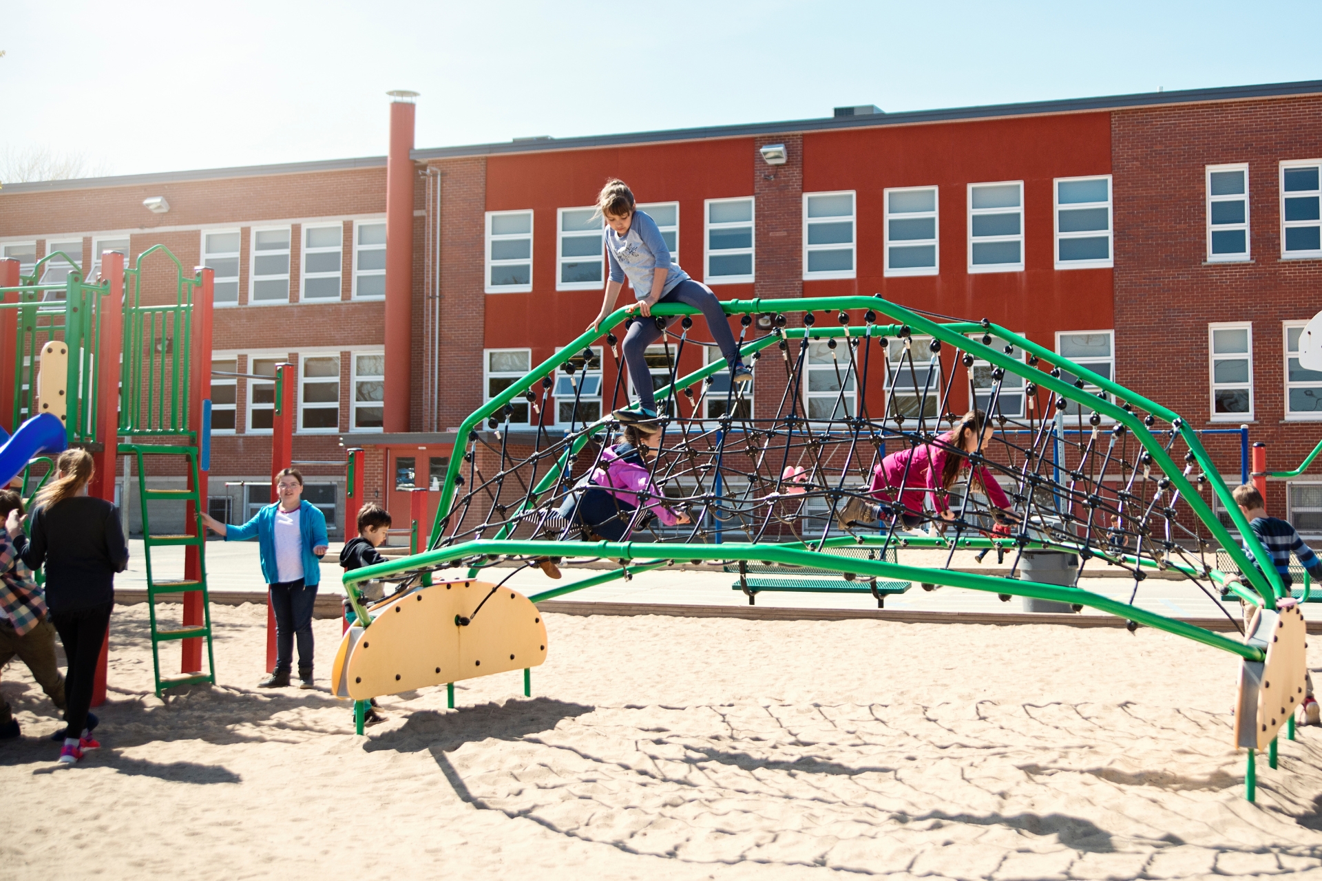 children playing on climbing structure at school or camp playground during outdoor activity