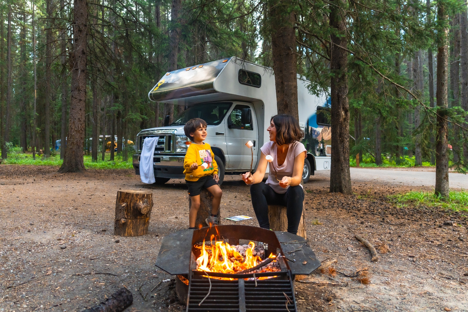 family sitting by campfire at campground during outdoor community program or camp activity
